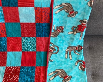 Modern Baby or Toddler Blanket. Cotton Patchwork Top (red, teal). Fleece backing Sock Monkey design in red and light blue.