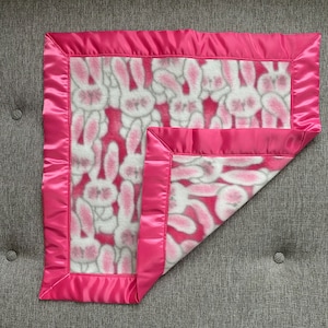 Fleece baby or toddler small security blanket (lovey) in pattern of cute white bunnies on a pink background, with pink satin trim