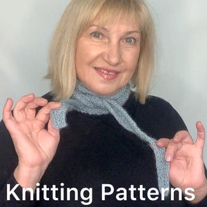 May include: A woman wearing a light blue knitted scarf. The scarf is held up by the woman's hands. The text "Knitting Patterns Sophie scarf" is at the bottom of the image.