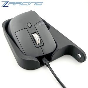 Op de afbeelding: Een zwarte computermuis met een zilveren scrollwiel en het Logitech-logo, in een zwarte houder. De houder heeft een gebogen ontwerp met een gat aan de zijkant. De tekst "Z RACING" staat in blauw linksboven.