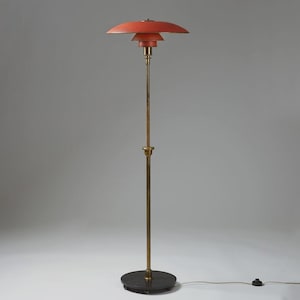 May include: A vintage floor lamp with a tiered, coral-colored shade and a brass-toned stem. The lamp has a circular black base and a power cord. The design is reminiscent of mid-century modern lighting.