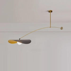 May include: Modern ceiling light fixture with a brass finish. The fixture features a curved arm with a gray and yellow shade and a spherical light bulb. The design is minimalist and elegant, suitable for contemporary interiors.
