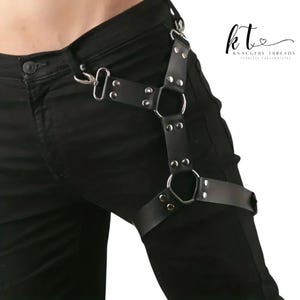 May include: Black leather leg harness with silver metal hardware. The harness has adjustable straps, metal rings, and rivets. The brand name "kt Knaughty Threads Fearless Fashionistas" is visible in the upper right corner.