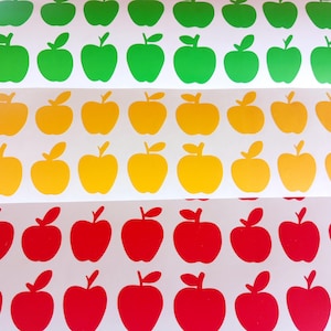 Puede incluir: Hojas de pegatinas con forma de manzana en verde, amarillo y rojo. Cada hoja está llena de filas de diseños de manzanas, con una pequeña hoja y un detalle de tallo. Las pegatinas están dispuestas sobre un fondo blanco.