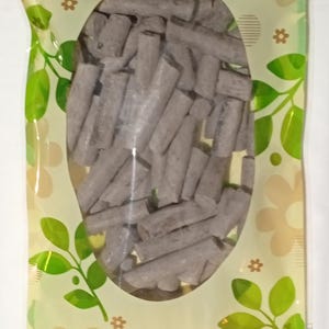 Pode incluir: Um saco pl&aacute;stico transparente com uma grande janela oval preenchida com numerosos objetos cil&iacute;ndricos cinzentos. O saco tem um fundo amarelo claro com padr&otilde;es florais e de folhas em verde e castanho.