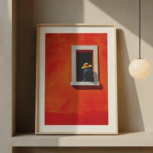 Puede incluir: Impresión artística enmarcada que representa a una persona con un sombrero amarillo mirando por una ventana. La obra de arte está situada contra una pared naranja vibrante, con un marco de ventana blanco. La impresión está enmarcada en un marco de madera clara.