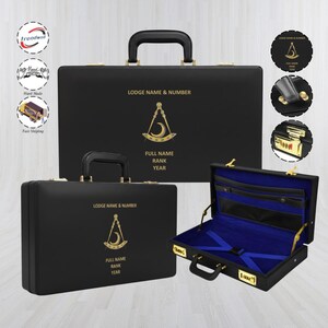 May include: Black briefcase with gold hardware and a handle. The case features a Masonic symbol and text that reads "LODGE NAME & NUMBER", "FULL NAME", "RANK", and "YEAR". The interior is lined with blue fabric.