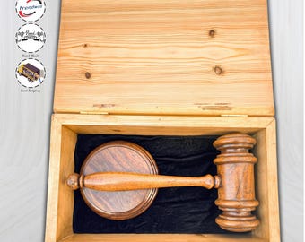 Op de afbeelding: Een houten hamer en klankblokset in een open, lichtbruine houten kist. De hamer en het klankblok zijn donkerbruin en liggen op een zwarte fluwelen voering. De kist is gemaakt van lichtbruin hout.