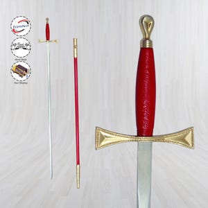 May include: A decorative sword with a red handle and a gold crossguard. The blade is silver. A red and gold staff is also present. The sword is displayed against a light wood-grain background.
