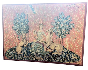May include: A tapestry depicting a woman in a blue dress with a unicorn and a lion in a forest setting. The tapestry has a red background with green trees and a floral pattern.