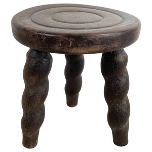 May include: A dark brown wooden stool with three twisted legs and a round top.