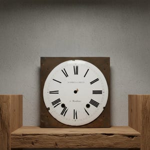 May include: A vintage clock face with black Roman numerals on a white background. The clock face is mounted on a square, brown metal plate. The text "SCHMIDT & FREUD" and "à Moulins" are visible. The clock face is displayed on a wooden shelf.
