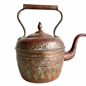 Peut inclure: Une bouilloire en cuivre antique avec un design orné. La bouilloire a une poignée et un bec en laiton, et une patine verte à la surface.