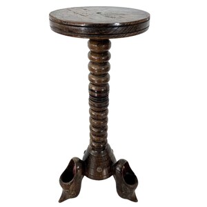 Könnte beinhalten: Ein dunkelbrauner Holz-Stehtisch mit runder Tischplatte und einer einzigartigen, spiralförmigen Säule. Die Basis hat drei geschnitzte, klauenartige Füße.