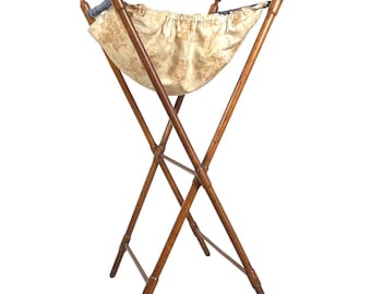 May include: A wooden folding clothes hamper with a fabric liner. The hamper is made of natural wood and has a simple, classic design.
