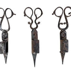 May include: Three antique metal candle snuffers with ornate handles and a pointed tip. The snuffers are rusty and have a dark brown patina.
