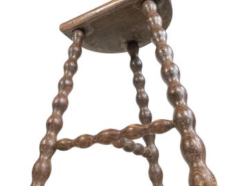 May include: A wooden stool with a rounded seat and turned legs. The legs are made of dark brown wood and have a twisted design.