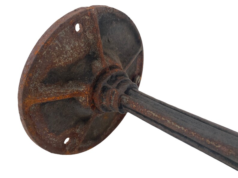 May include: A rusty metal base with a round plate and a long, cylindrical stem. The base is designed to be mounted to a wall or surface.
