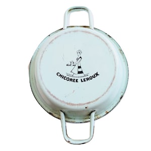 Puede incluir: Una olla de esmalte azul claro vintage con dos asas. La olla tiene un logotipo en blanco y negro que dice "Chicoree Leroux" y presenta a una mujer con un vestido a rayas sosteniendo una bandeja.