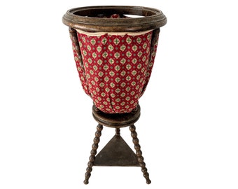 May include: A wooden stand with a red and green patterned fabric liner. The stand has a round top and three legs with a beaded design.