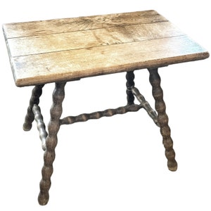 Op de afbeelding: Een rustieke houten tafel met een rechthoekig blad en gedraaide poten. De tafel is gemaakt van donkerbruin hout en heeft een natuurlijke afwerking.