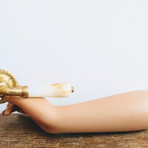 May include: A gold door handle with a white marble knob. The handle has a rope design around the edge.