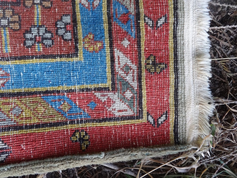 May include: Close-up of the edge of a red, blue, and yellow patterned rug with white fringe.