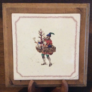 Peut inclure: Un carreau vintage avec un cadre en bois présente une illustration colorée d'une personne portant un panier d'objets blancs. La personne porte une tenue rouge et verte et un chapeau bleu.
