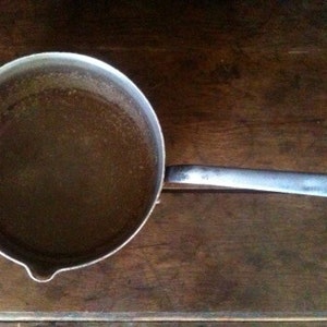 Peut inclure: Une casserole en argent avec un liquide brun à l'intérieur. La casserole a une longue poignée.