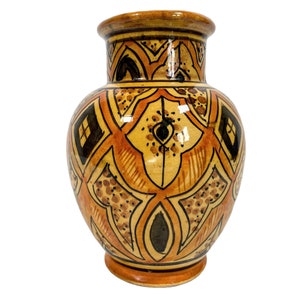 May include: A ceramic vase with a geometric pattern in shades of brown, orange, and black. The vase has a rounded body and a narrow neck.