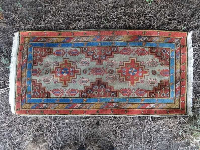 May include: A traditional rug with a geometric pattern in shades of red, blue, and beige. The rug has a white fringe border.