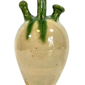 May include: A ceramic pitcher with a green glaze and three spouts. The pitcher has a rounded body and a handle.