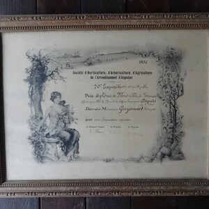 May include: A framed black and white certificate with an ornate frame. The certificate is for a prize awarded in 1936 by the Society of Horticulture, Arboriculture, and Agriculture of the Arrondissement of Argentas. The certificate features a drawing of a woman standing in a garden.