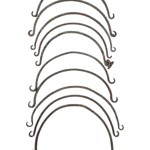 May include: A set of ten rusty metal hoops, stacked on top of each other. The hoops are all the same size and shape, and they are all slightly bent.