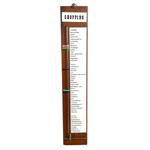 May include: A wooden shopping list with a sliding metal marker. The list includes items such as meat, fish, bread, vegetables, fruit, dairy, and household goods. The list is titled "SHOPPING".
