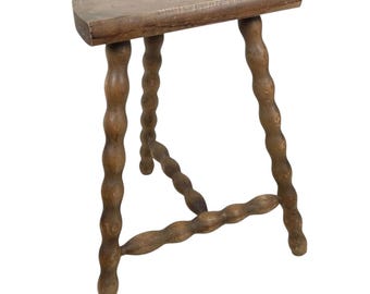 May include: A wooden stool with a half-round seat and turned legs. The legs are connected by a stretcher.