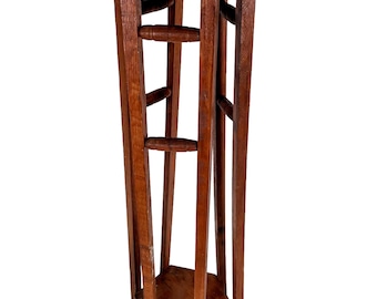 May include: A tall, wooden plant stand with a round top and a hexagonal base. The stand is made of dark brown wood and has a rustic, vintage look.