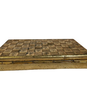 May include: A gold metal box with a checkered pattern on the lid. The box has a hinged lid and is closed.