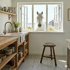 Könnte beinhalten: Eine rustikale Küche mit Holzarbeitsplatten, offenen Regalen und einem weißen Bauernhaus-Waschbecken. Ein weißes Pferd blickt durch ein offenes Fenster. Ein Holzschemel steht auf dem weiß gestrichenen Boden. Verschiedene Keramikgläser und -schalen sind sichtbar.