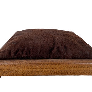Peut inclure: Un lit pour chien rectangulaire brun avec un dessus en tissu pelucheux brun et un cadre en bois.