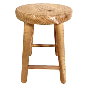 Op de afbeelding: Een eenvoudige houten kruk met een ronde zitting en vier poten. De kruk is gemaakt van natuurlijk hout en heeft een rustieke uitstraling.