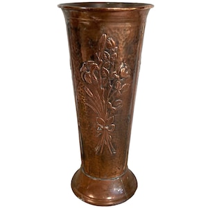 May include: A hammered copper vase with a floral design. The vase is tall and slender with a wide base. The floral design is embossed and features roses, lilies, and other flowers.