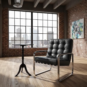 May include: A black leather armchair with a tufted back and chrome frame sits in a room with a large window overlooking a city. A small, black side table is next to the chair. The room has exposed brick walls and hardwood floors.