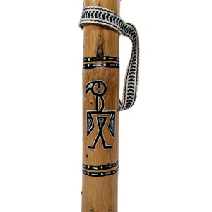 May include: A wooden tube with a black and white patterned strap. The tube is decorated with black and white geometric designs, including a stylized bird figure.