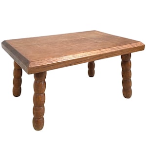 May include: A wooden table with a rectangular top and four turned legs. The table is made of light brown wood and has a natural finish.