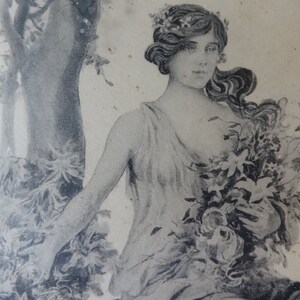 May include: A black and white vintage illustration of a woman with long flowing hair wearing a floral crown and a flowing gown. She is holding a bouquet of flowers in her hands.