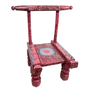 May include: A red wooden chair with intricate carvings and a circular design on the seat. The chair has a high back and four legs.