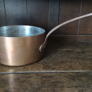 以下が含まれることがあります： 長い湾曲したハンドルが付いた小さな銅製の鍋。鍋は光沢のある金属製の仕上げで、ヴィンテージのようです。