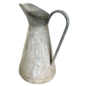 May include: A vintage galvanised metal pitcher with a worn, distressed finish. The pitcher has a wide mouth and a handle.
