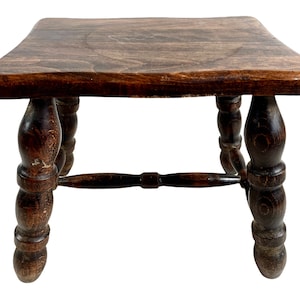 Peut inclure: Un tabouret en bois brun foncé avec des pieds tournés et un plateau carré.